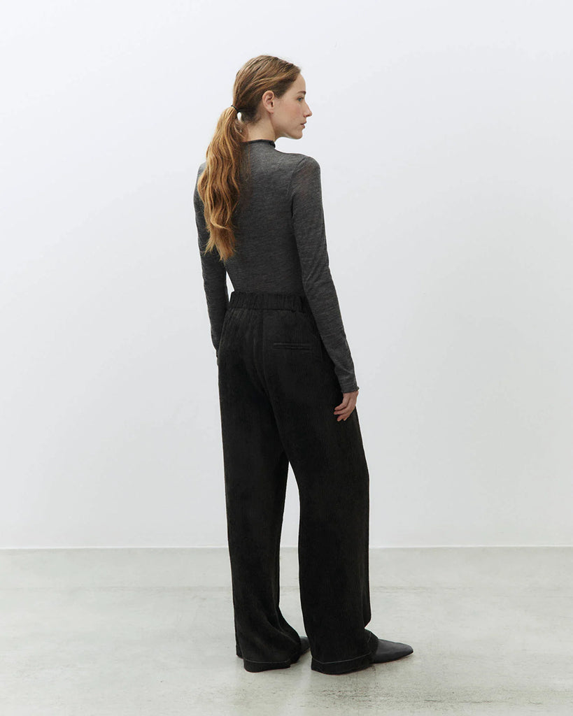 Sztruksowe, luźne spodnie Velvet Rib Carbone ze średnim stanem i szerokimi nogawkami. Posiadają kontrastujące, kremowe przeszycia i pas z ozdobnymi guzikami i gumką z tyłu. Mają jedną kieszeń wpuszczaną z tyłu. Zapinane na guzik i ukryty zamek błyskawiczny.&nbsp;