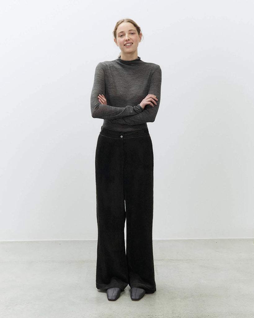 Sztruksowe, luźne spodnie Velvet Rib Carbone ze średnim stanem i szerokimi nogawkami. Posiadają kontrastujące, kremowe przeszycia i pas z ozdobnymi guzikami i gumką z tyłu. Mają jedną kieszeń wpuszczaną z tyłu. Zapinane na guzik i ukryty zamek błyskawiczny.&nbsp;