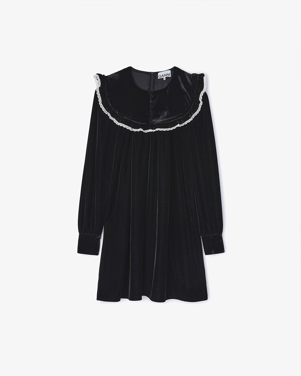 Welurowa, mini sukienka Velvet Black marki GANNI z dużym, zaokrąglonym kołnierzem z kontrastowym, koronkowym obszyciem i długimi, lekko bufiastymi rękawami. Rękawy zakończone są eleganckimi mankietami. Z przodu, na kołnierzu widoczny jest rząd małych, powlekanych materiałem guzików. Sukienka ma swobodny fason, który lekko rozszerza się ku dołowi.&nbsp;

-Zamów sukienkę w swoim standardowym rozmiarze