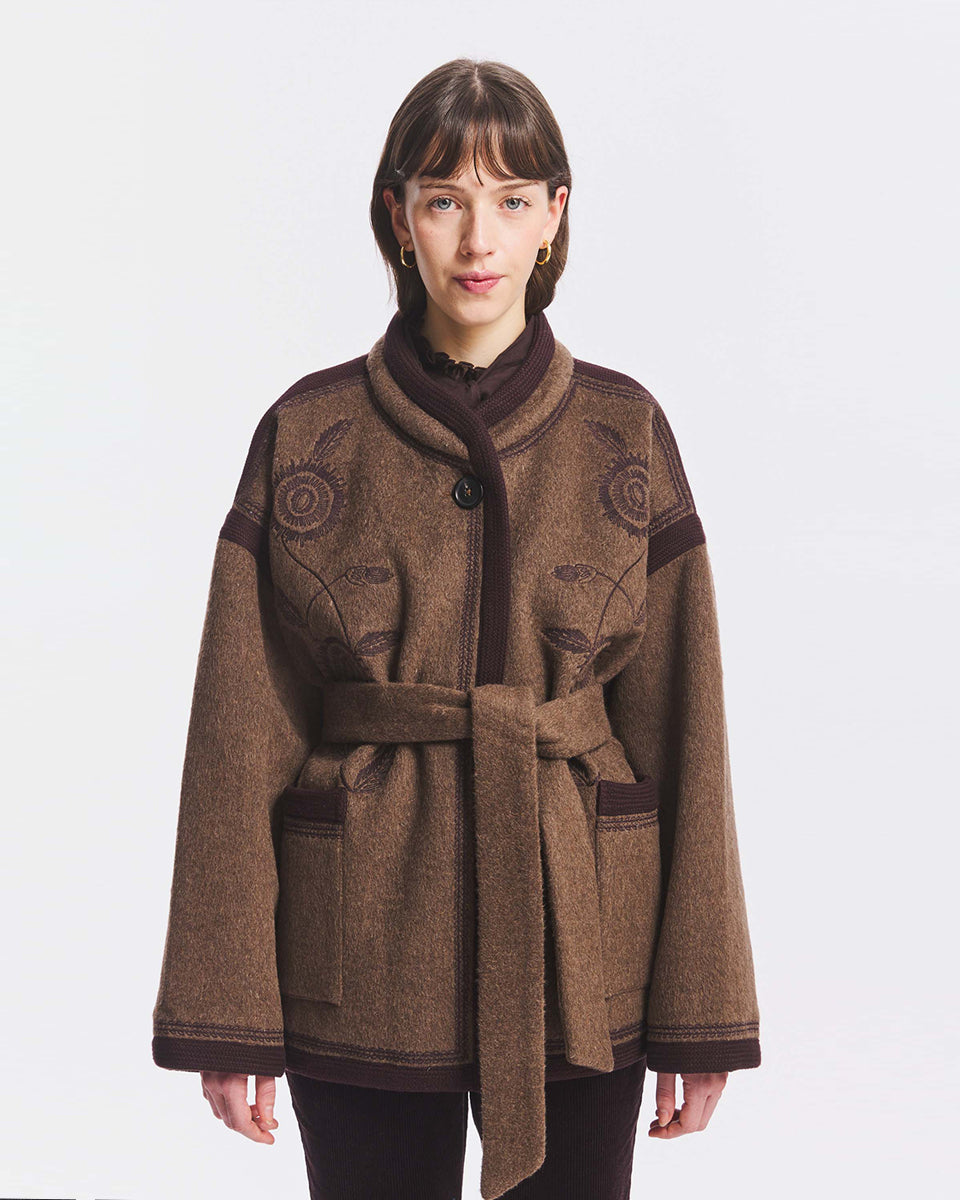 Wełniana kurtka w stylu kimono Willow Brown Antik Batik z ozdobnym haftem. Na piersi znajduje się utrzymany w tej samej tonacji, kunsztowny haft o motywie kwiatowym. Krawędzie wykończono lamówką. Zapinany na jeden widoczny przy kołnierzu guzik. &nbsp;Posiada podszewkę, dwie boczne kieszenie i odpinany pasek do wiązania. Kurtka stanowi wyrazisty element garderoby, który doda charakteru każdej stylizacji.&nbsp;

-Odpinany pasek do zawiązania w talii

-Posiada podszewkę&nbsp;

-Ciepła tkanina z wełną