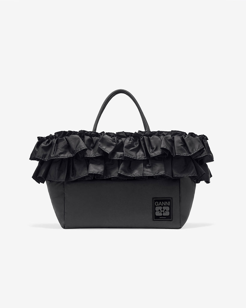Torba typu tote 7188 XXL Shopper Black marki GANNI z uchwytami. Posiada jedną dużą komorę z wewnętrzną kieszenią zapinaną na zamek. U dołu znajduje się niewielkie logo marki. Wyjątkowości dodaje zdobienie w postaci falbanek. Zaprojektowana, aby pomieścić telefon, portfel, okulary przeciwsłoneczne, klucze, butelkę z wodą, saszetkę, strój sportowy i laptopa.