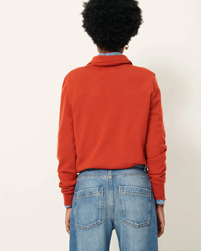 Sweter polo Yanaka Vitamin marki Sessun w kolorze ceglasto-czerwonym z długim rękawem, zakończonym prostym mankietem i kołnierzykiem zapinanym na ozdobne guziki. Wykonany z cienkiej wełny merino. Wykonany z bawełnianej dzianiny.