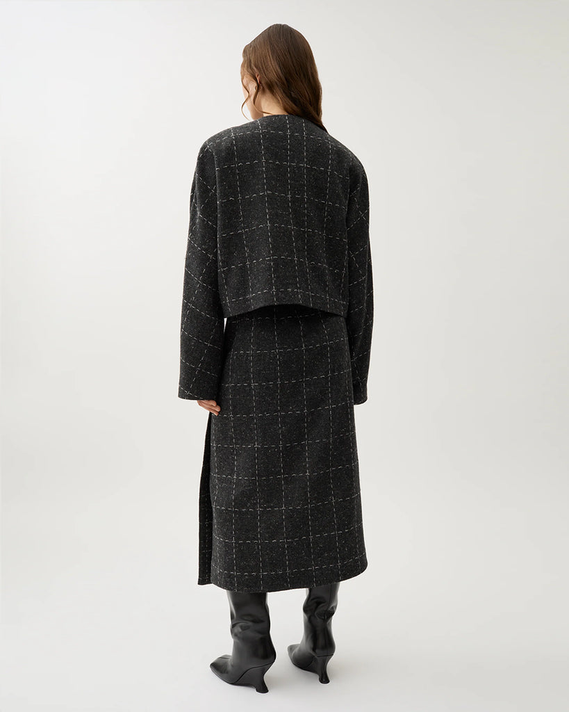 Krótka, luźna marynarka Zola Check Grey Melange w kolorze ciemnoszarym w kratkę z szerokimi rękawami i okrągłym dekoltem. Jest zapinana na jeden guzik pod szyją i posiada kieszenie boczne. Wykonana z mieszanki wełny. Zestaw ją z spódnicą Blanket Check lub ulubionymi jeansami.&nbsp;